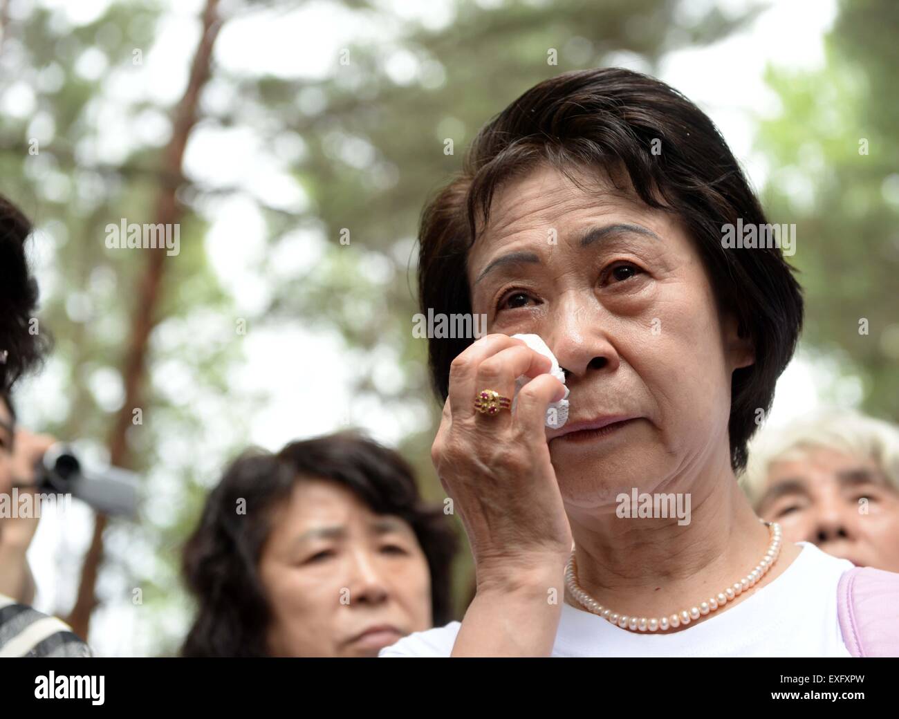 (150714) -- HARBIN, July 14, 2015 (Xinhua) -- Ikeda Sumie, director general of a Tokyo support group for those Japanese returned from China, weeps in front of a grave in a cemetery to memorize adoptive Chinese parents in Fangzheng County near Harbin, capital of northeast China's Heilongjiang Province, July 13, 2015. A group of 54 Japanese citizens, all now orphans, on Monday paid a visit to the graves of their adoptive Chinese parents here. Abandoned by their birth parents during the hasty retreat at the end of World War II in 1945, the orphans, now over 70 years old, were taken in and raised Stock Photo
