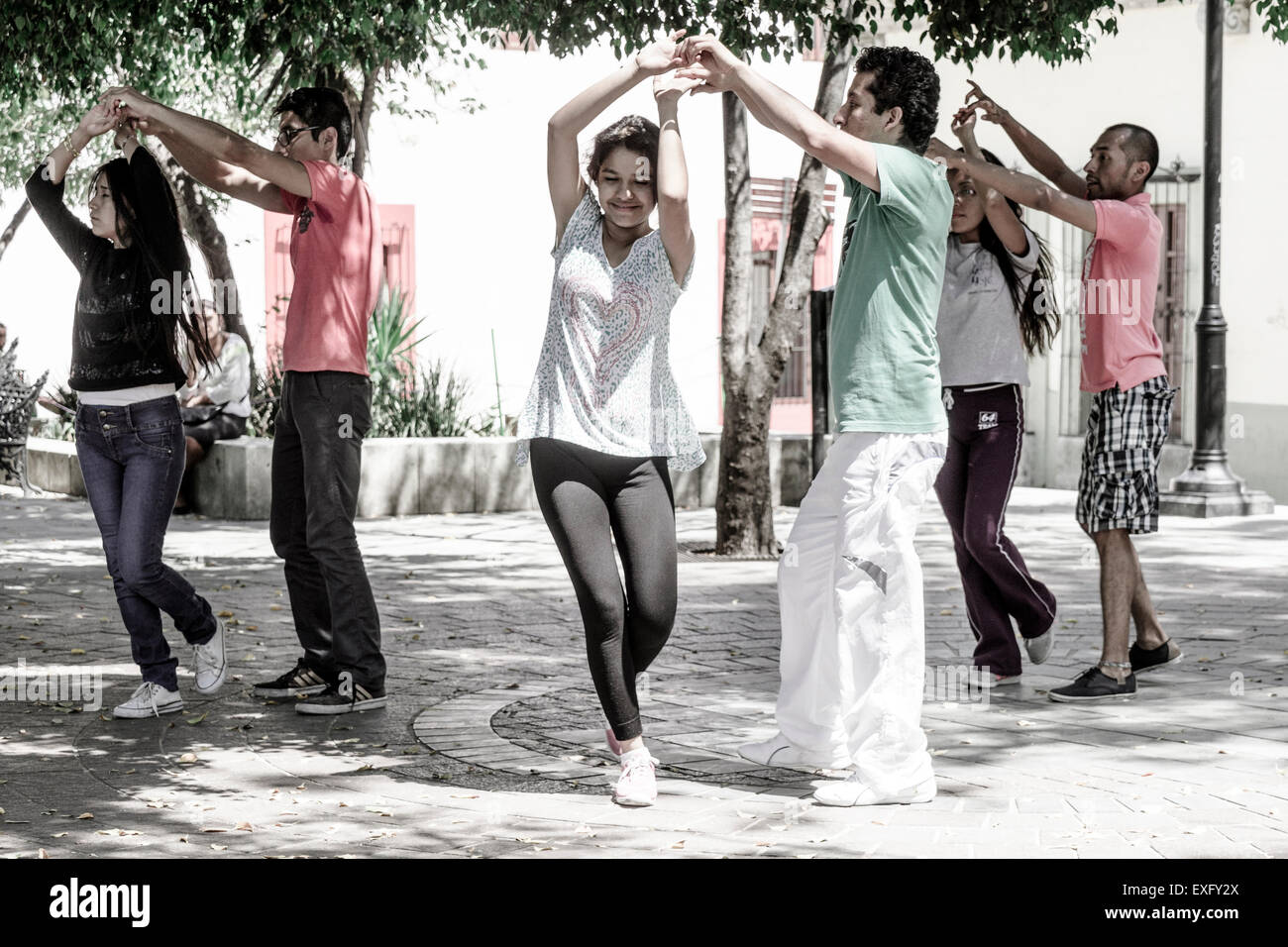 Three young Hispanic couples practicing salsa dancing in an outdoor courtyard in Oaxaca Mexico Stock Photo