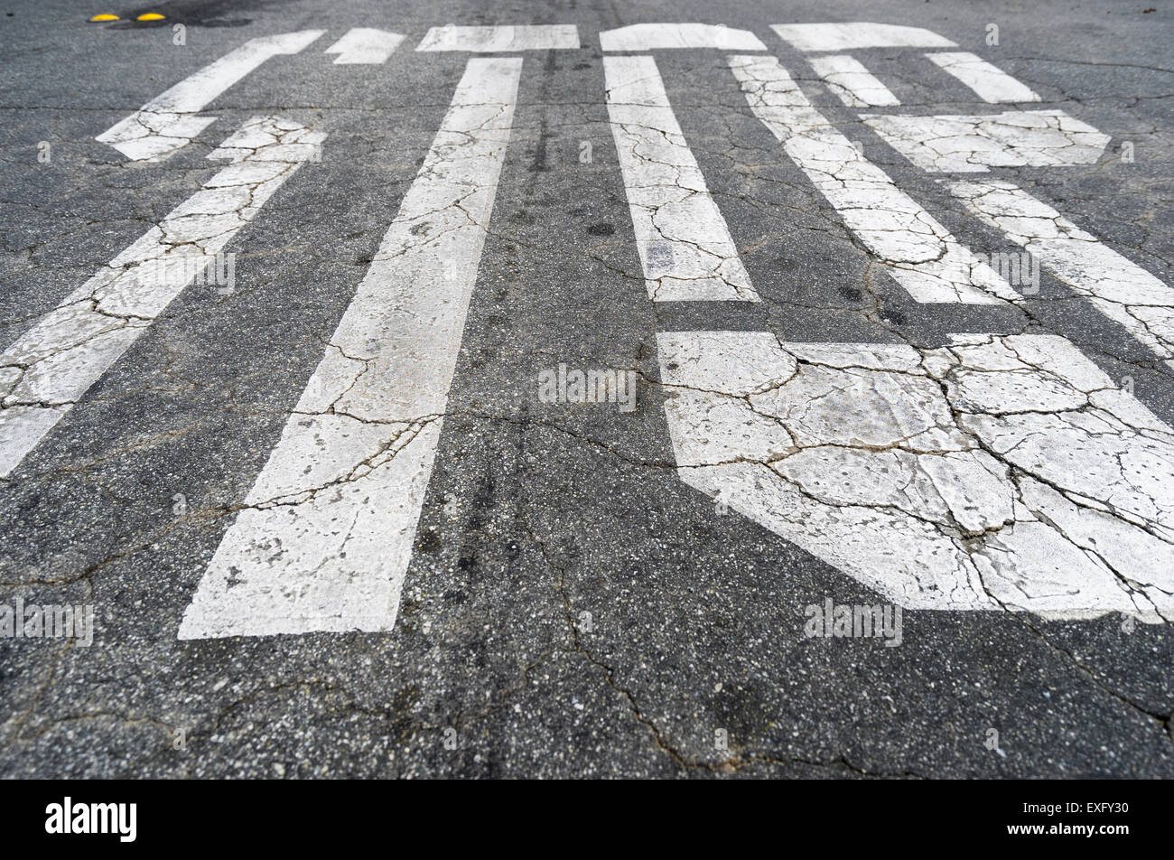 The word Stop painted on the road with cracks in the pavement Stock Photo
