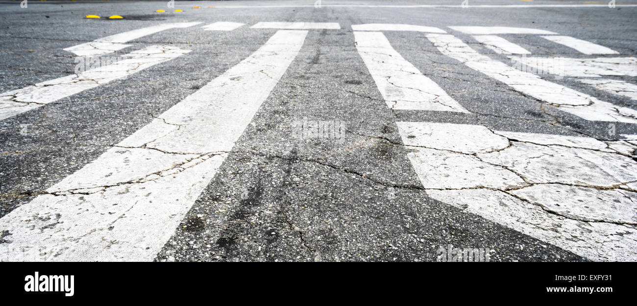 The word STOP painted on the road with cracks in the pavement Stock Photo