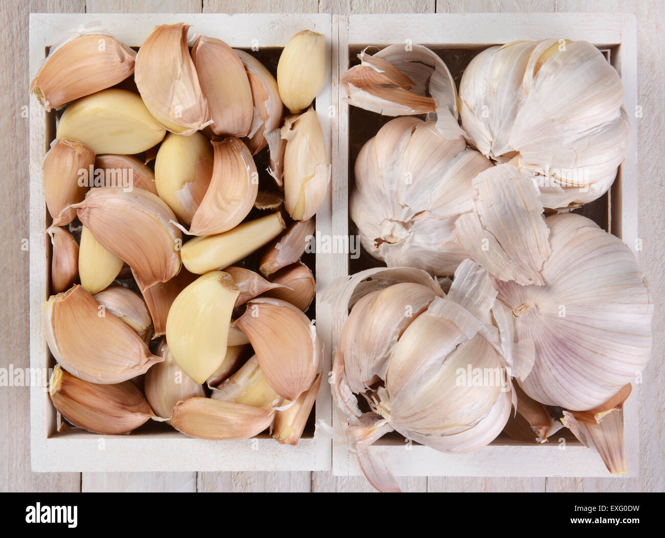 High angle view of garlic bulbs and cloves in small white wood crates. Stock Photo