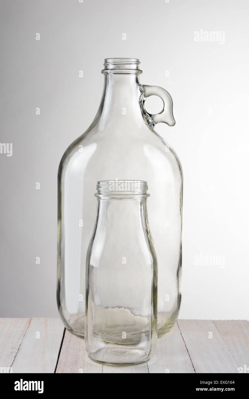 empty glass bottles clear two empty glass bottles small bottle in front of larger container vertical format against light to dark gray background stock empty glass bottles clear two empty glass bottles small bottle in front of larger container vertical format against light to dark gray background stock