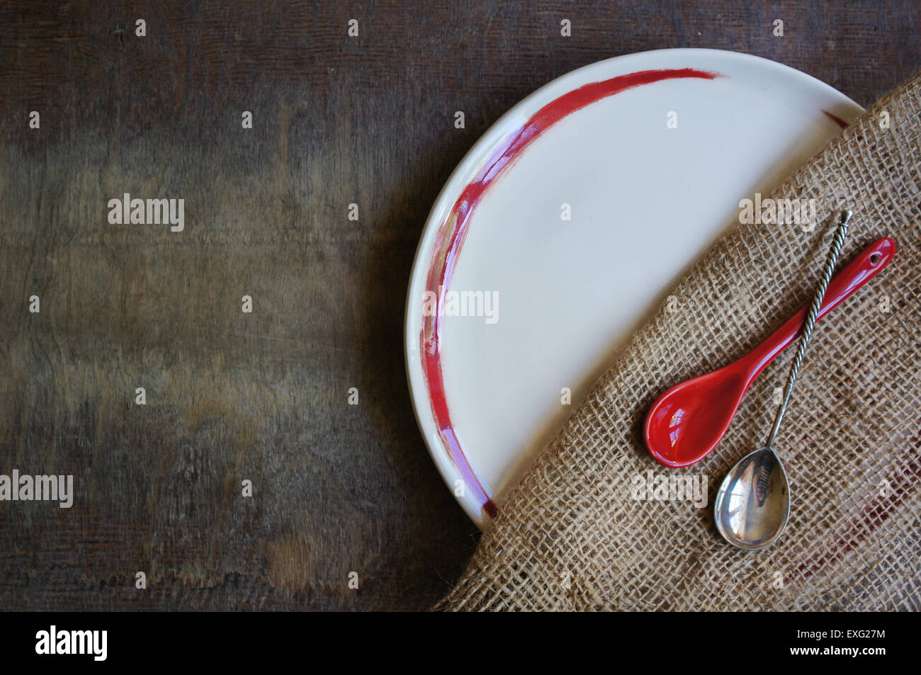 Plate and silverware on the old wooden table with burlap and napkin Stock Photo