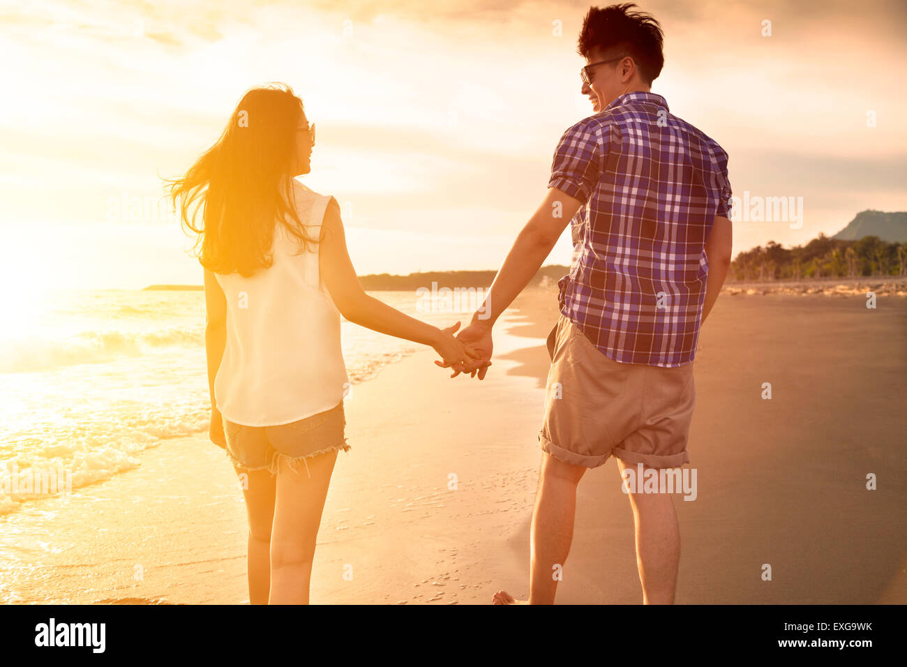 young couple enjoying a beach walk at sunset Stock Photo