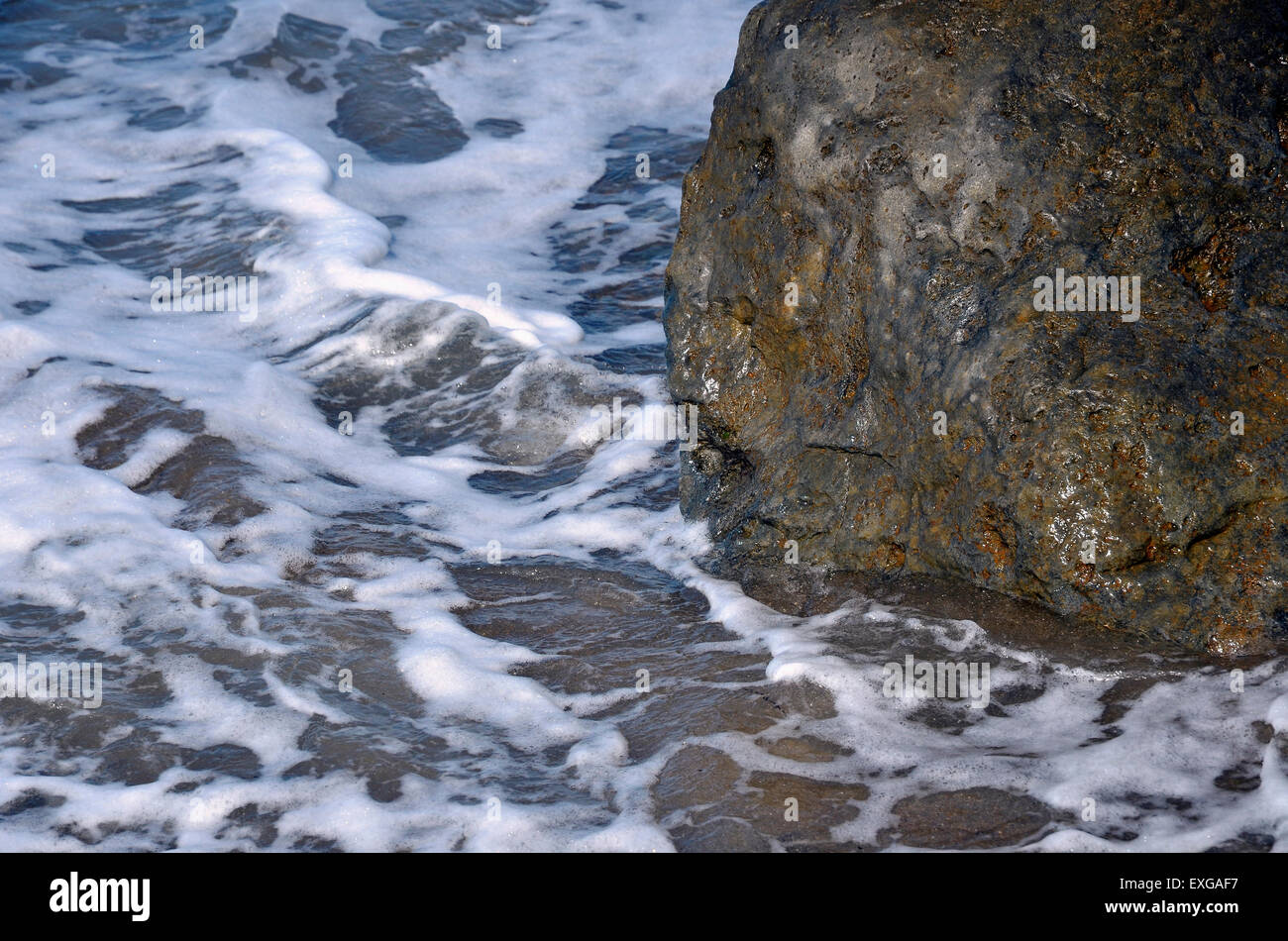 A calm sea washes around a rock armour groyne built for beach protection. Stock Photo