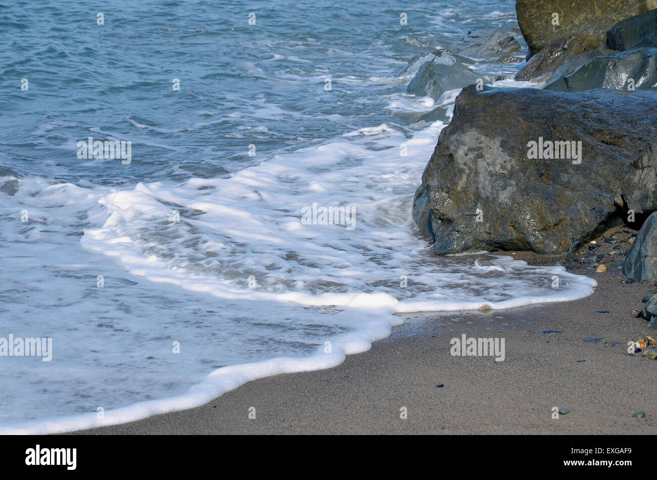 A calm sea washes around a rock armour groyne built for beach protection. Stock Photo