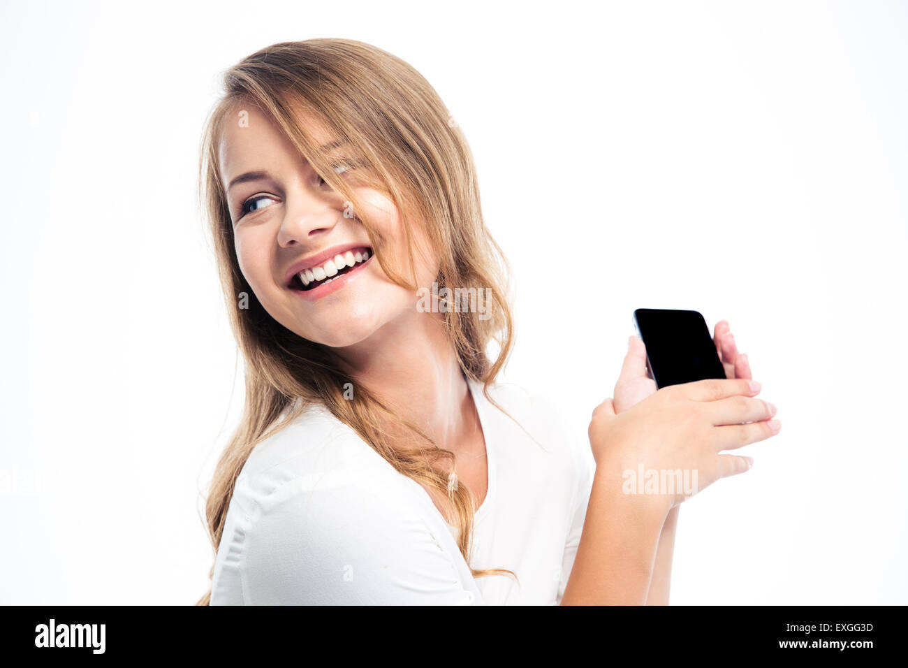 Smiling young girl holding smartphone isolated on a white background. Looking away Stock Photo