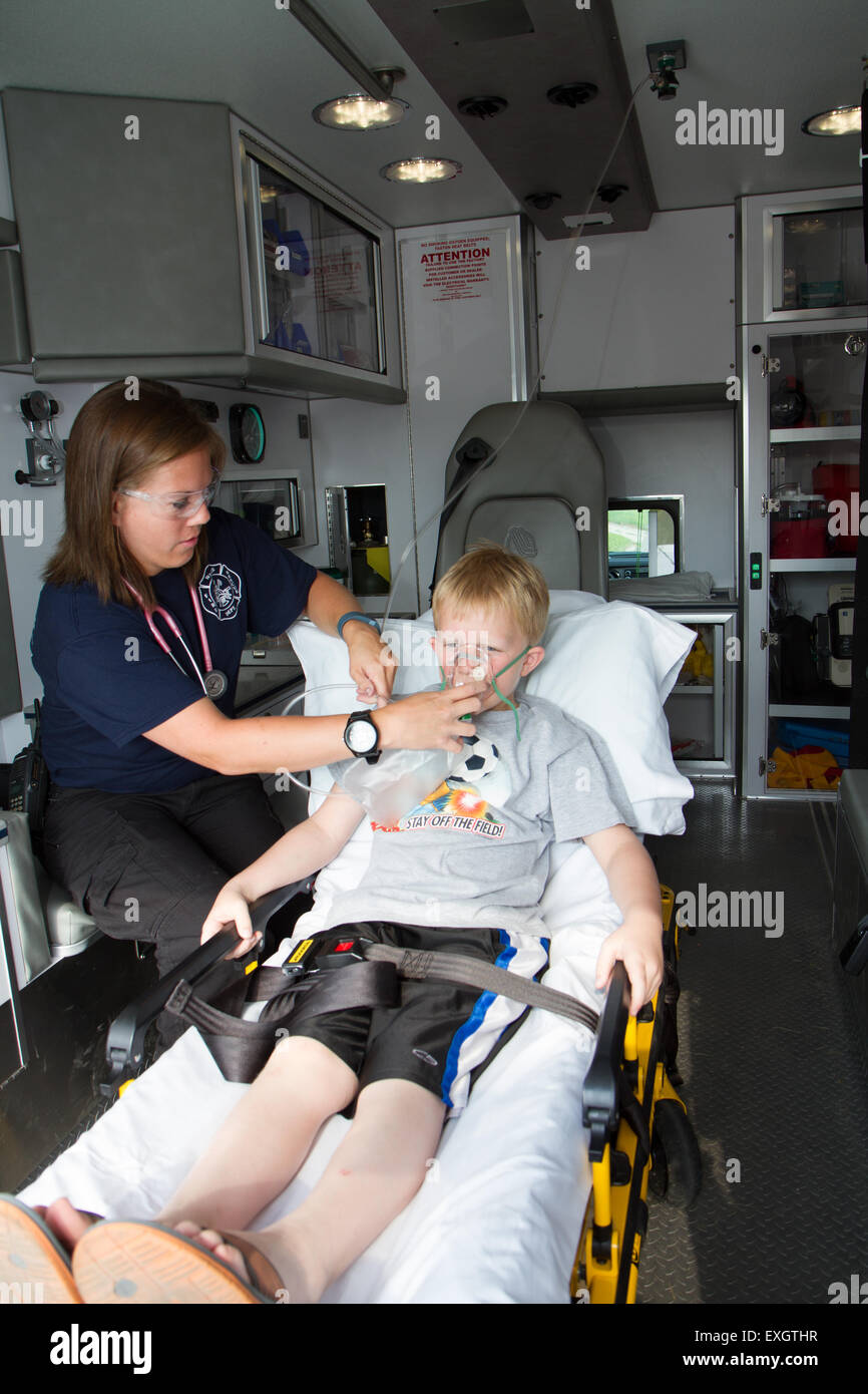 Female paramedic assisting young male patient in back of ambulance. Stock Photo