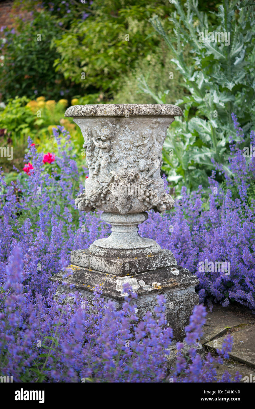 An old stone urn surrounded by blue catmint at Arley Hall gardens in Cheshire, England. Stock Photo