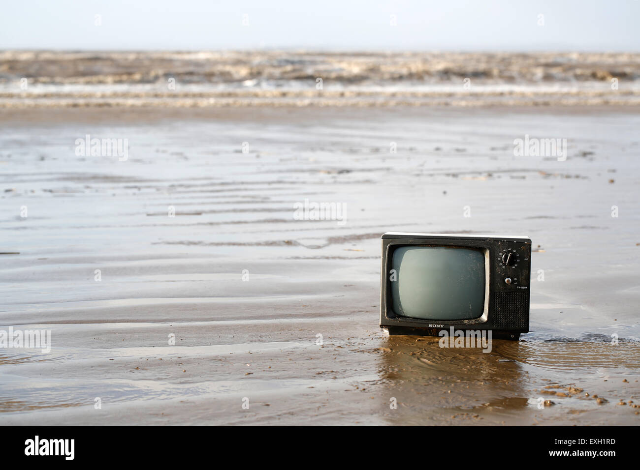 An old TV, washed up out of the sea onto an English sandy shoreline. Environmentally damaging to the beach at weston super mare, UK Stock Photo