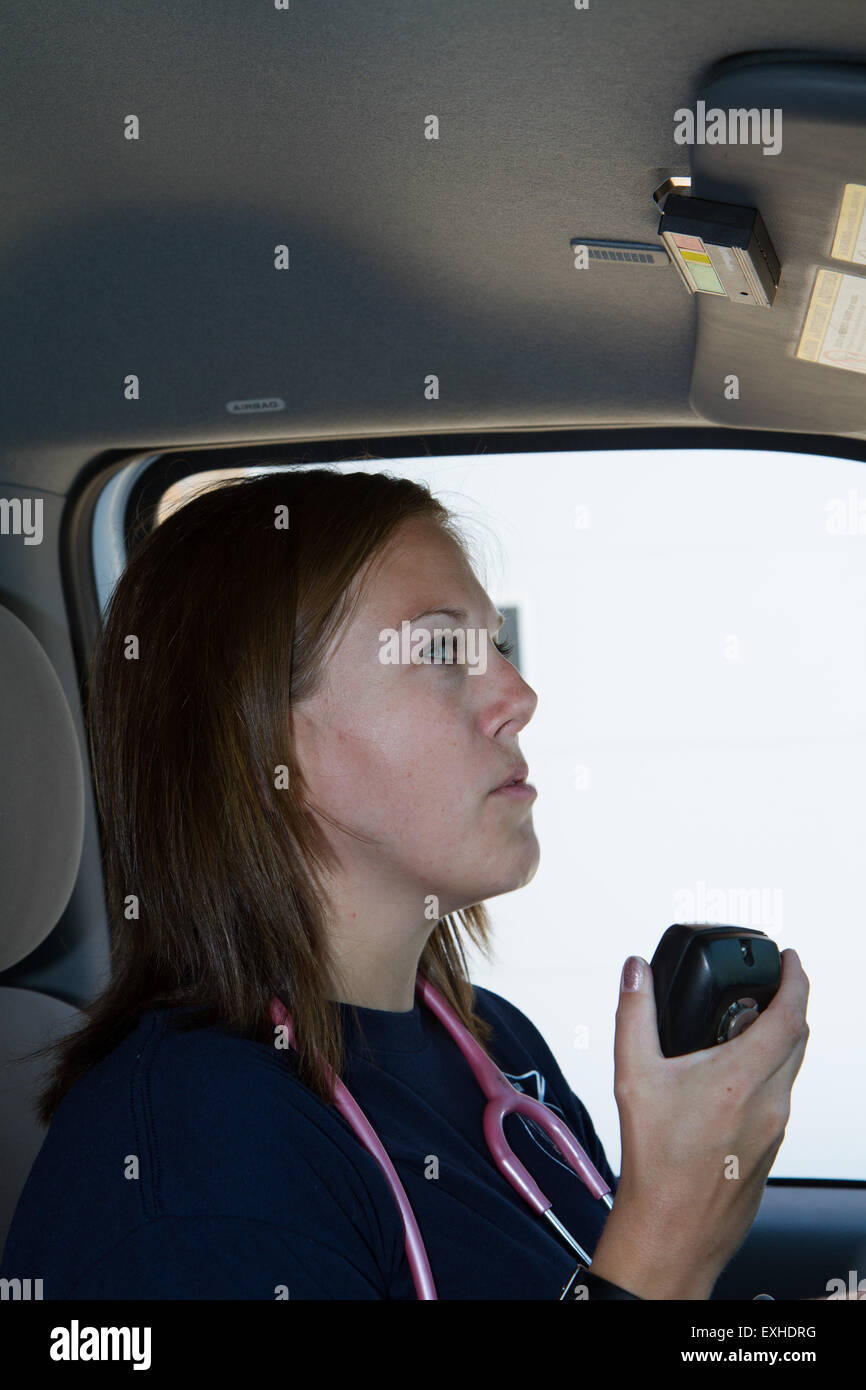 Female paramedic EMT using radio in ambulance. Rural volunteer fire department ambulance. Stock Photo