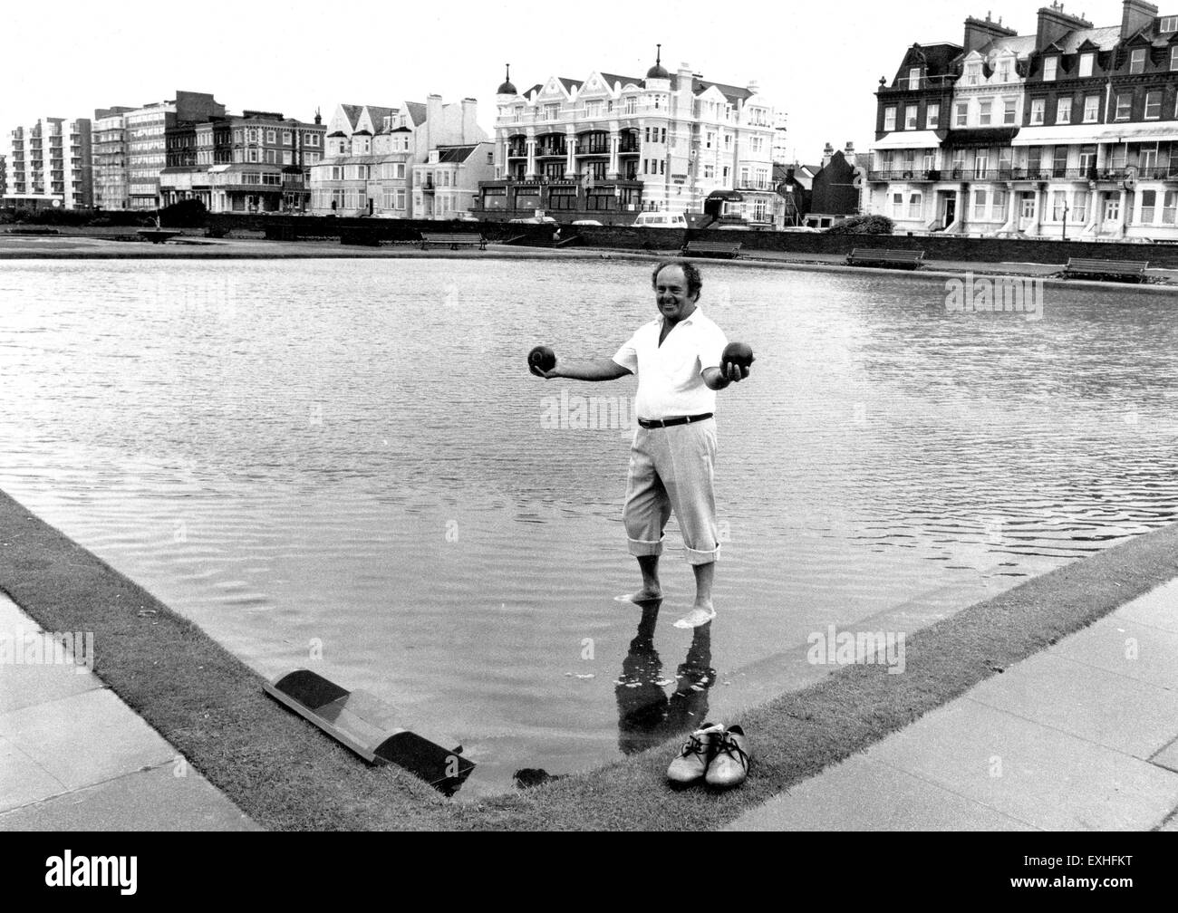 Man holding woods aloft on the flooded bowling greens along Hove seafront 1987 Stock Photo