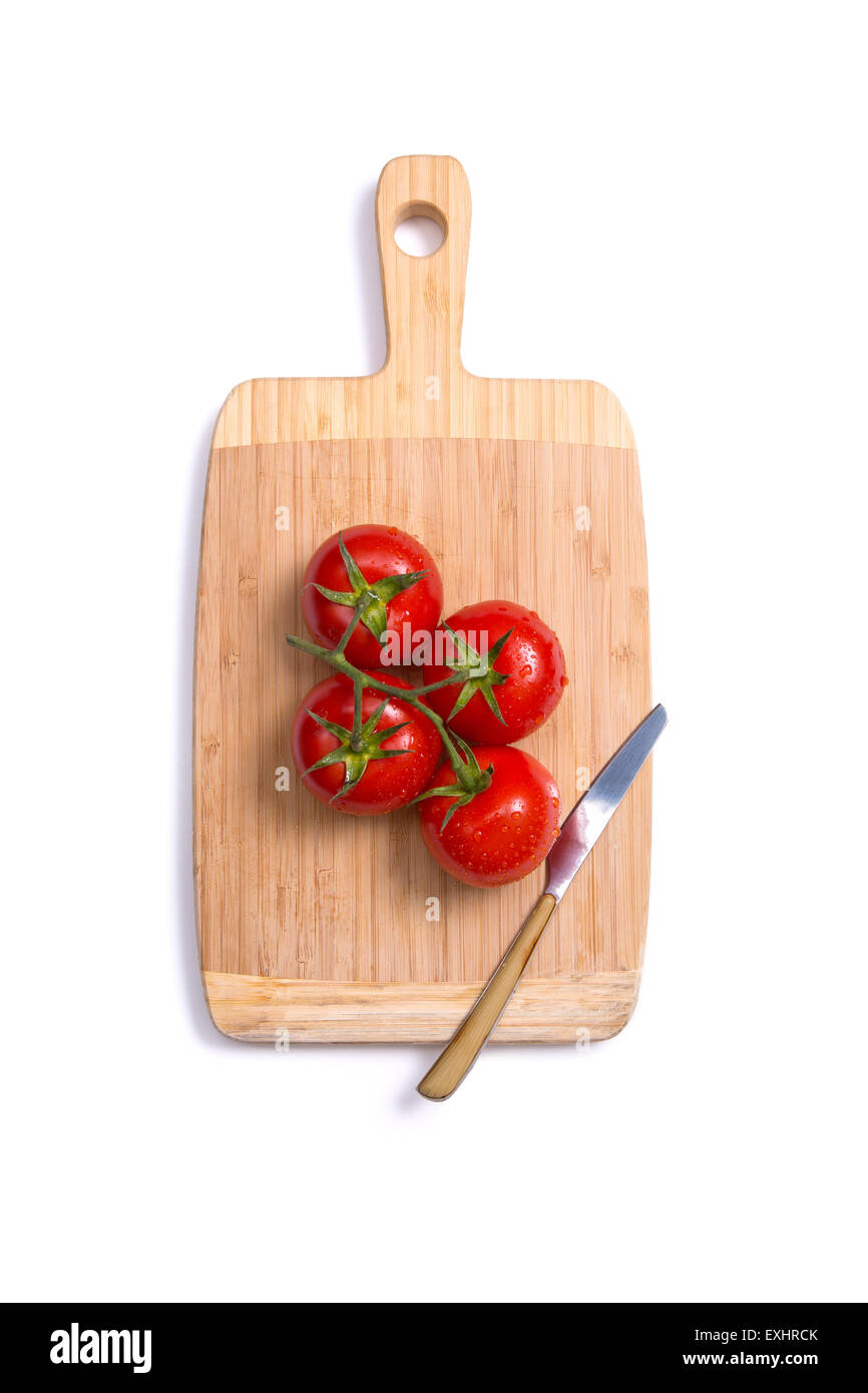 Top view of fresh tomatoes and a knife on chopping board, isolated on ...