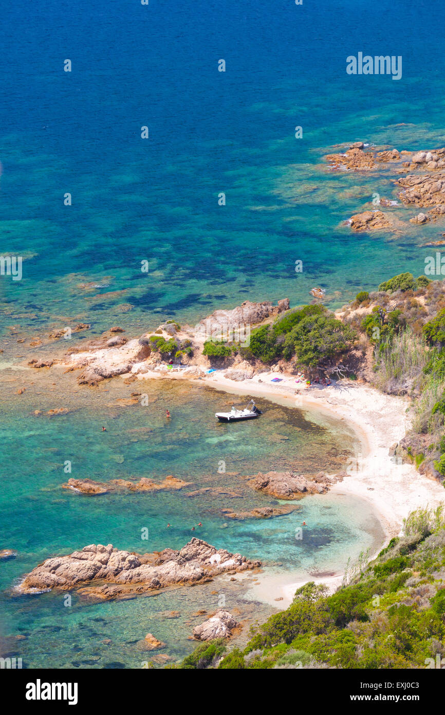 Corsica island, Cupabia gulf. Vertical coastal landscape with small motor boat near wild rocky beach Stock Photo