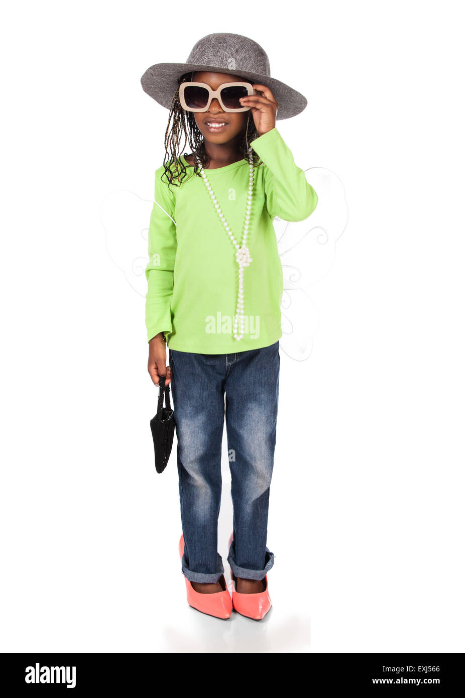 Adorable small african child with braids wearing a bright green shirt and blue jeans. The girl is playing dress up with a hat su Stock Photo