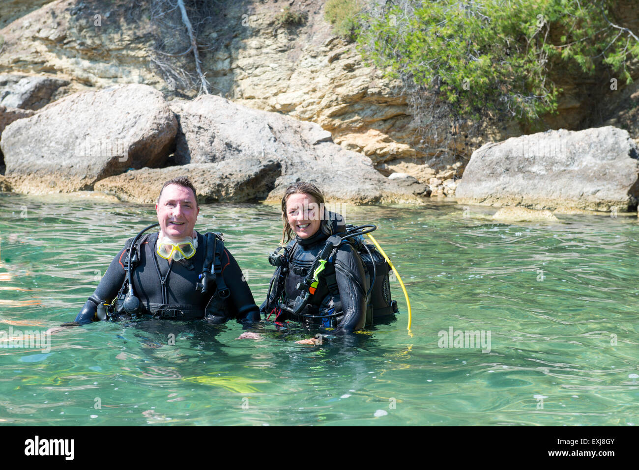 Two divers standing with their equipment standing in shallow water
