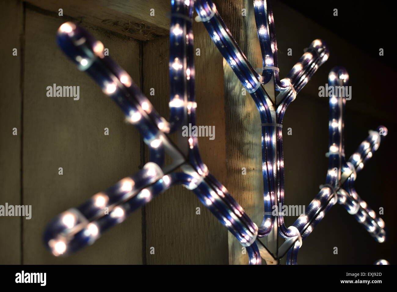 This is a Christmas light decoration outside a suburban house. The lights are in the shape of a snowflake hung on a fence. Stock Photo