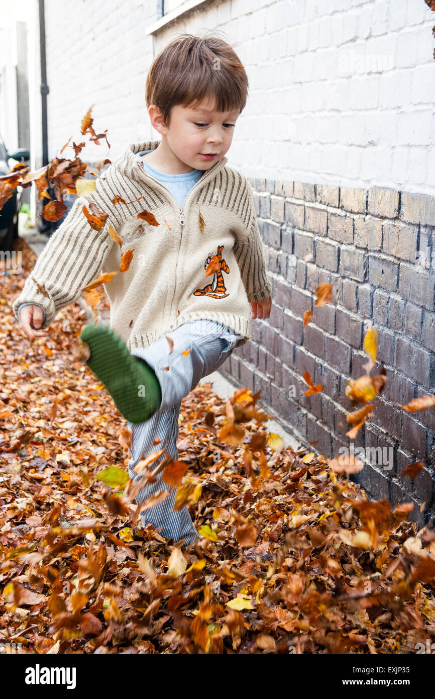Child kicking autumn leaves hi-res stock photography and images - Alamy
