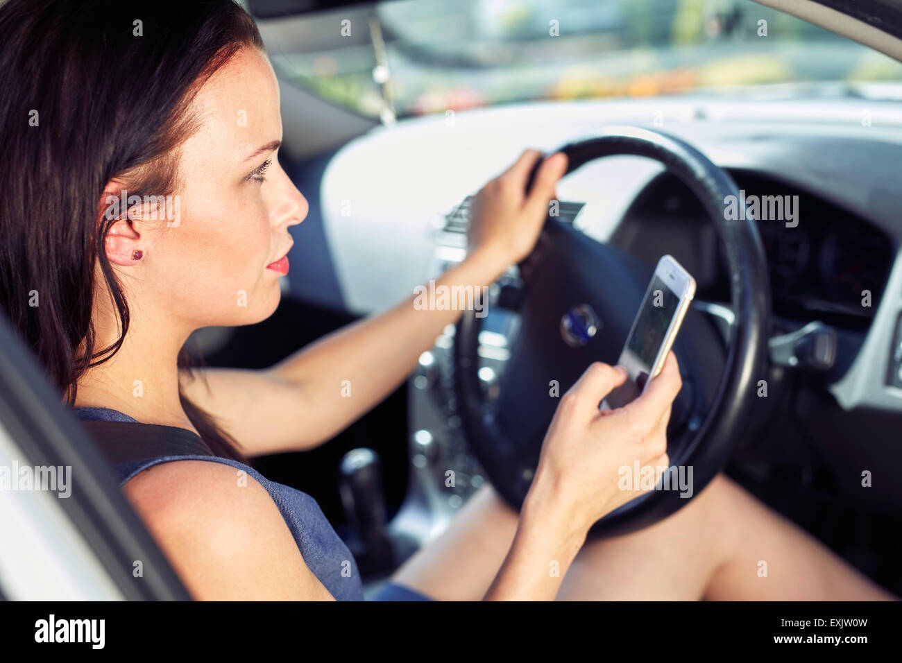 Woman using mobile phone whilst driving Stock Photo