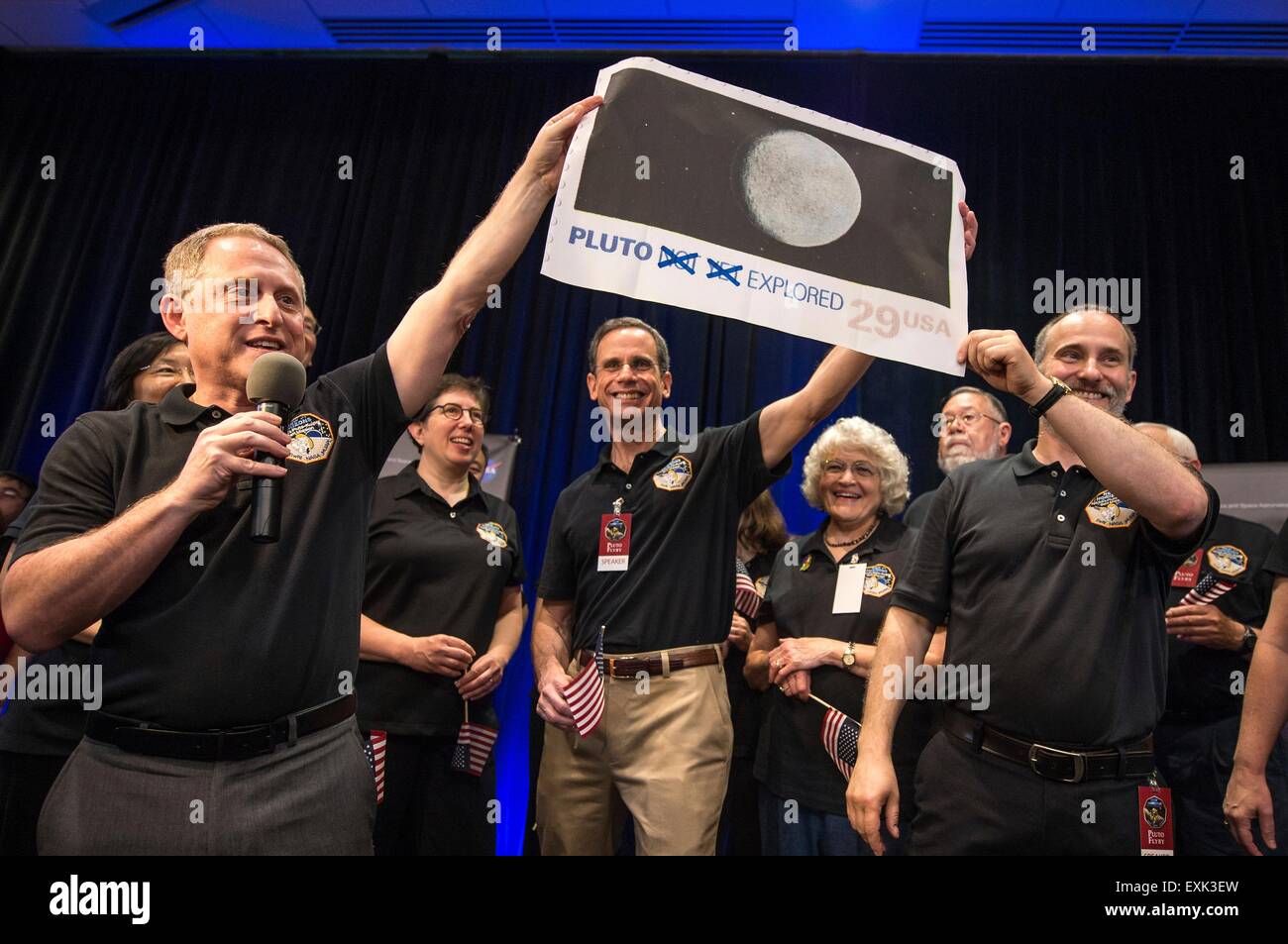 Laurel, Maryland, USA. 14th July, 2015. New Horizons Principal Investigator Alan Stern, left, Johns Hopkins University APL Director Ralph Semmel, center, and New Horizons Co-Investigator Will Grundy hold a print of an U.S. stamp with their suggested update since the New Horizons spacecraft has now explored Pluto July 14, 2015 in Laurel, Maryland. Stock Photo