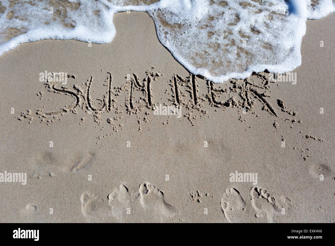 Inscription on beach sand. Sea shore close up with inscription. Summer Stock Photo