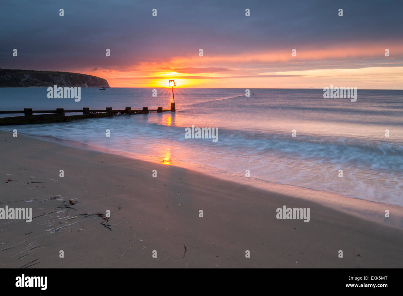 groyne in bay with sun rising through marker Stock Photo - Alamy