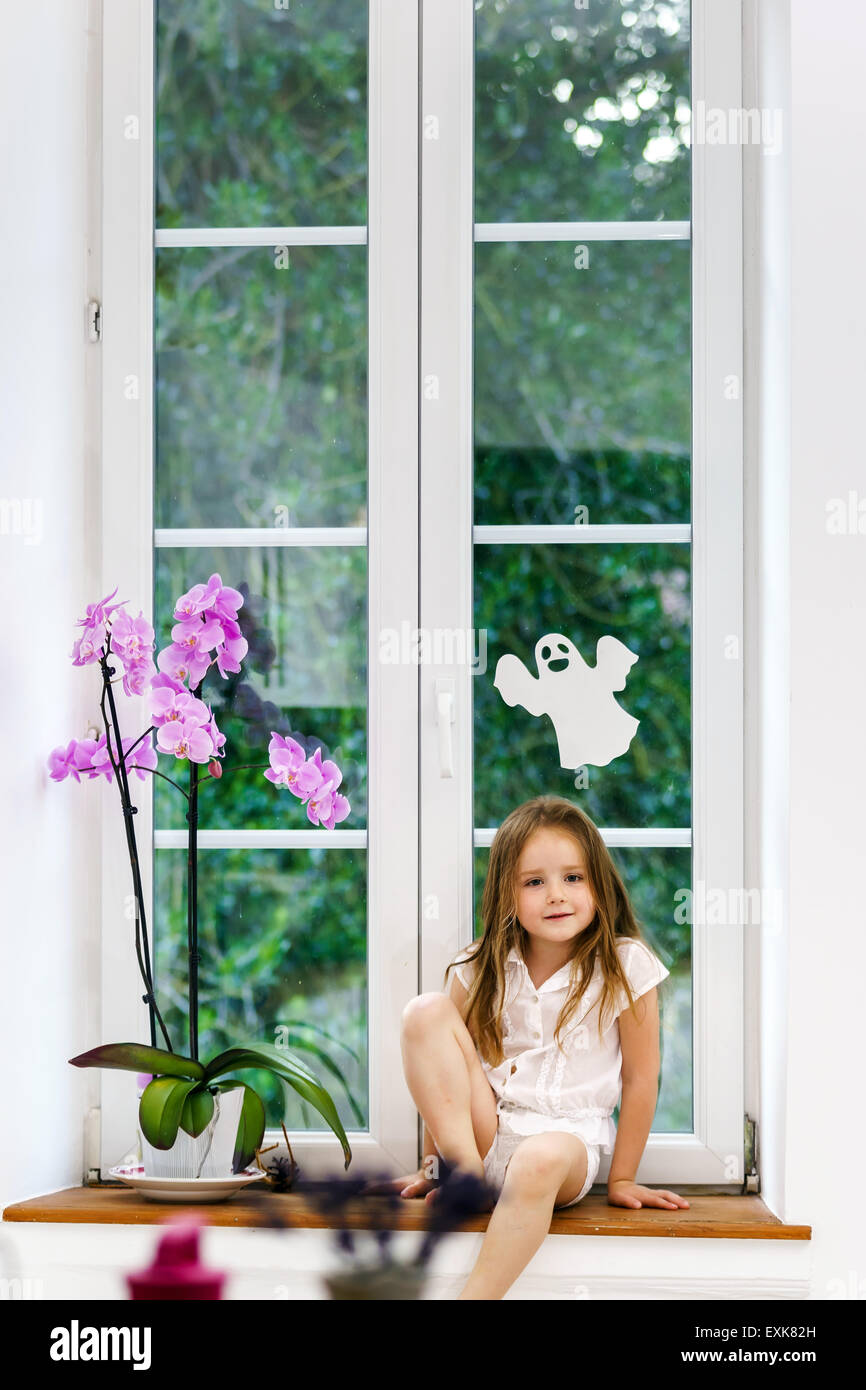 Cute little girl with flower sitting on windowsill, children safety ...