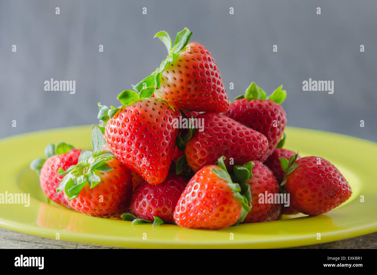 still life of fresh red strawberries on dish over wooden background ...