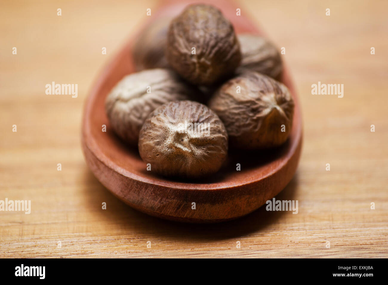 Nutmegs (Myristica fragrans) in a wooden spoon on wooden background Stock Photo