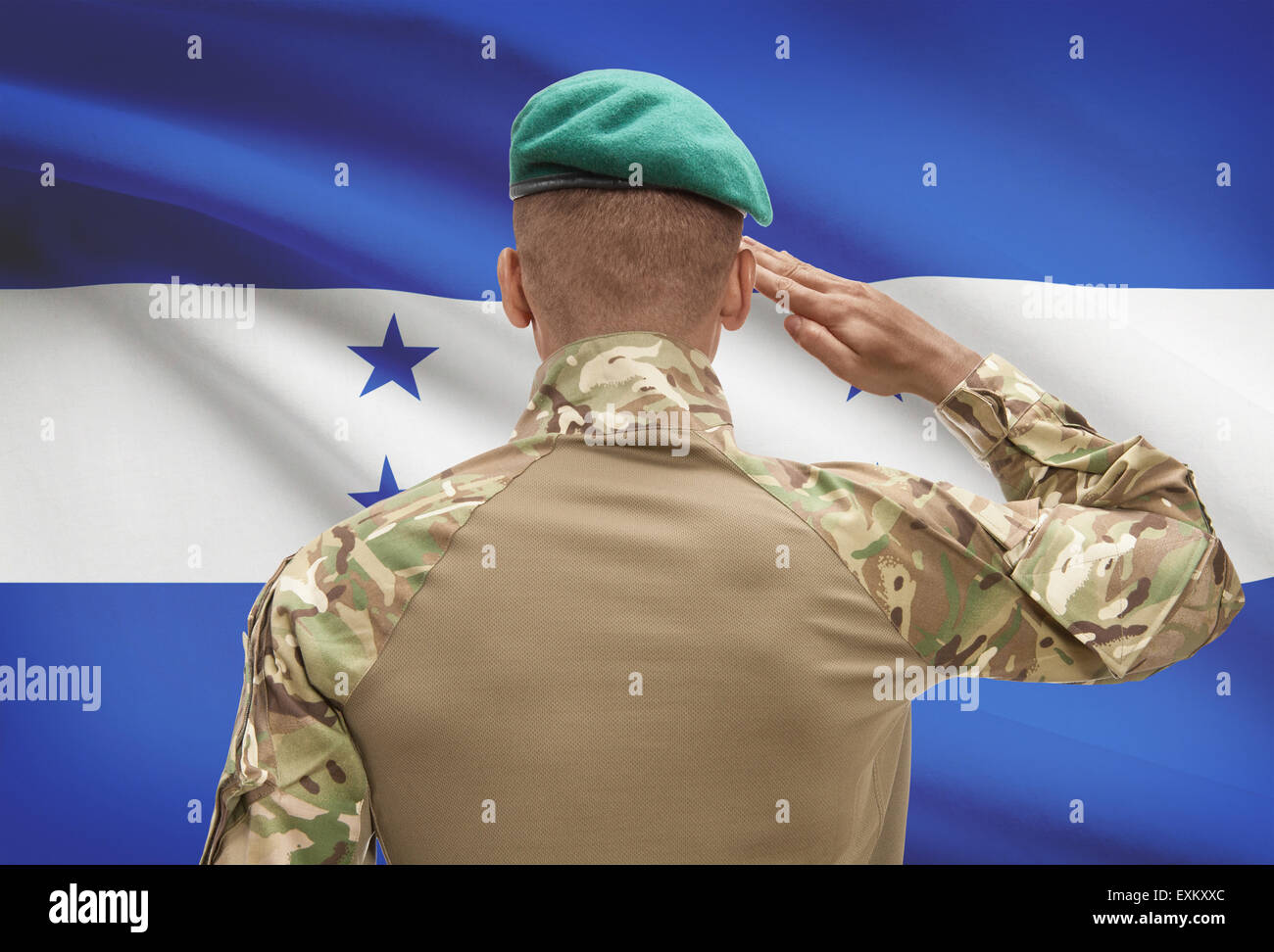 Dark-skinned soldier in hat facing national flag series - Honduras Stock Photo