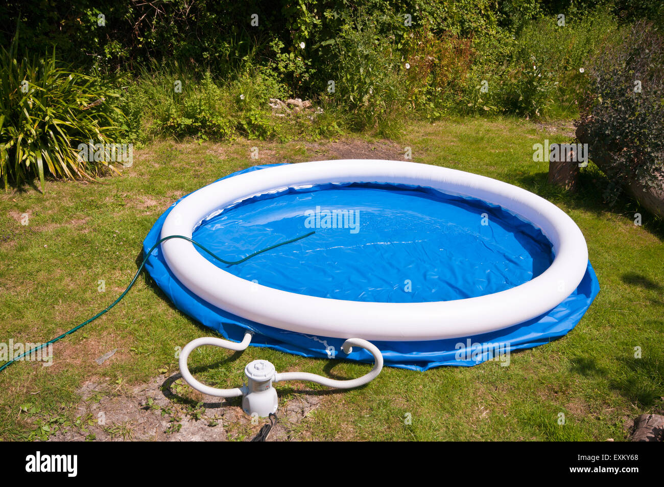 Filling A Paddling Pool With water from a Garden Hosepipe Hose Stock Photo