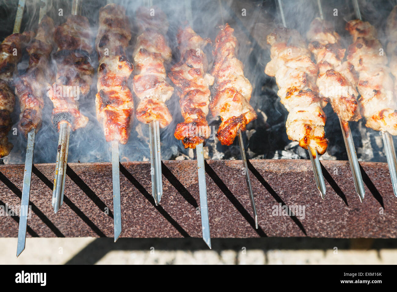 many shish kebab sticks preparing on outdoor grill Stock Photo