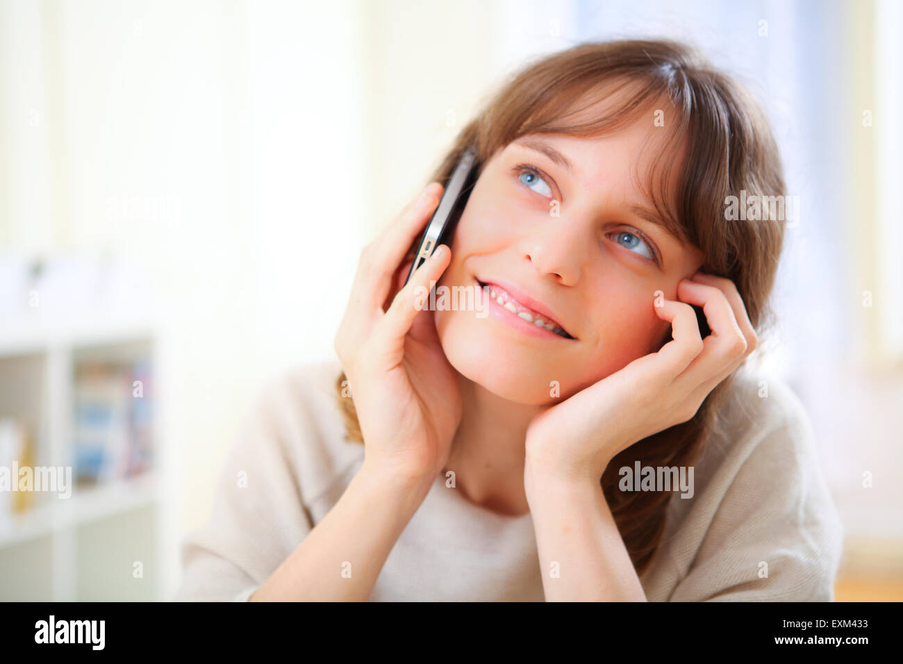 View of a young smiling woman talking on telephone Stock Photo