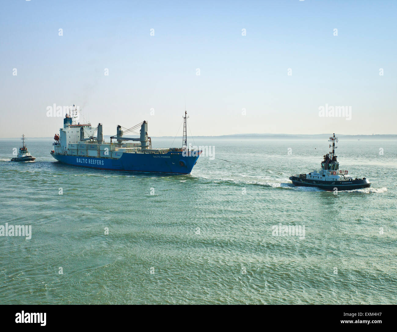 Cargo ship being towed into Portsmouth harbour. Stock Photo