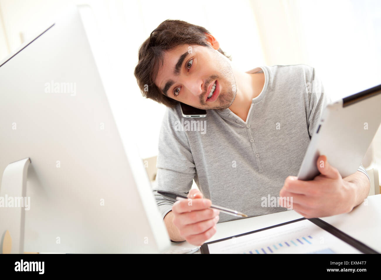 View of a young busy men at the office using tablet and smartphone Stock Photo