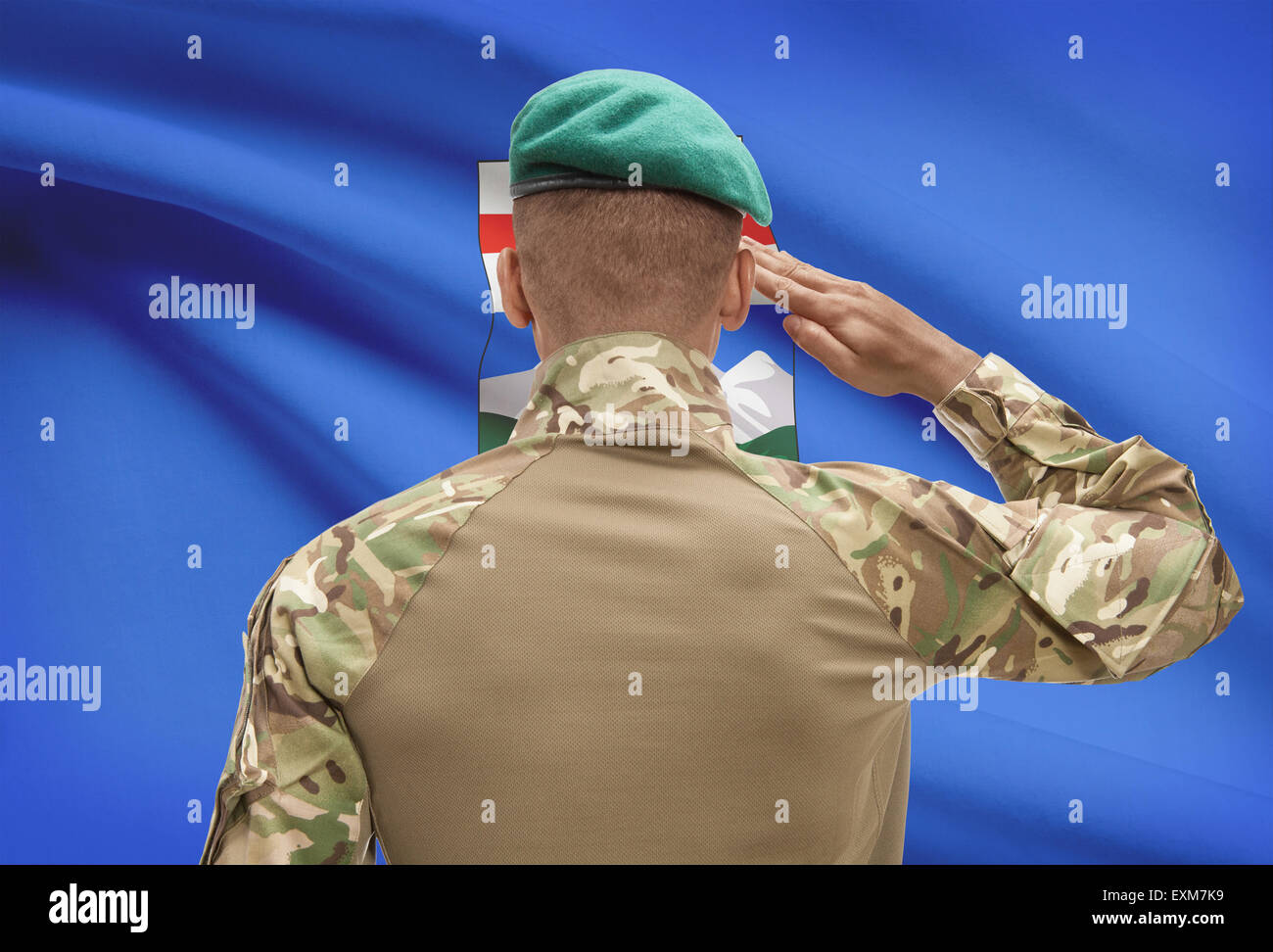 Dark-skinned soldier in hat facing Canadian province flag series - Alberta Stock Photo
