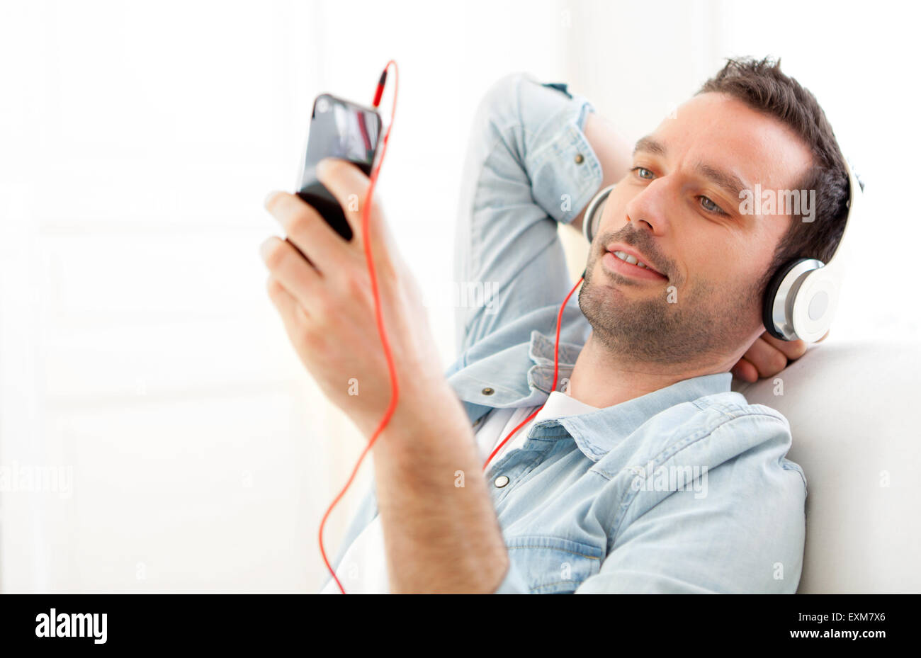 View of a Young relaxed man listening music in a sofa Stock Photo - Alamy