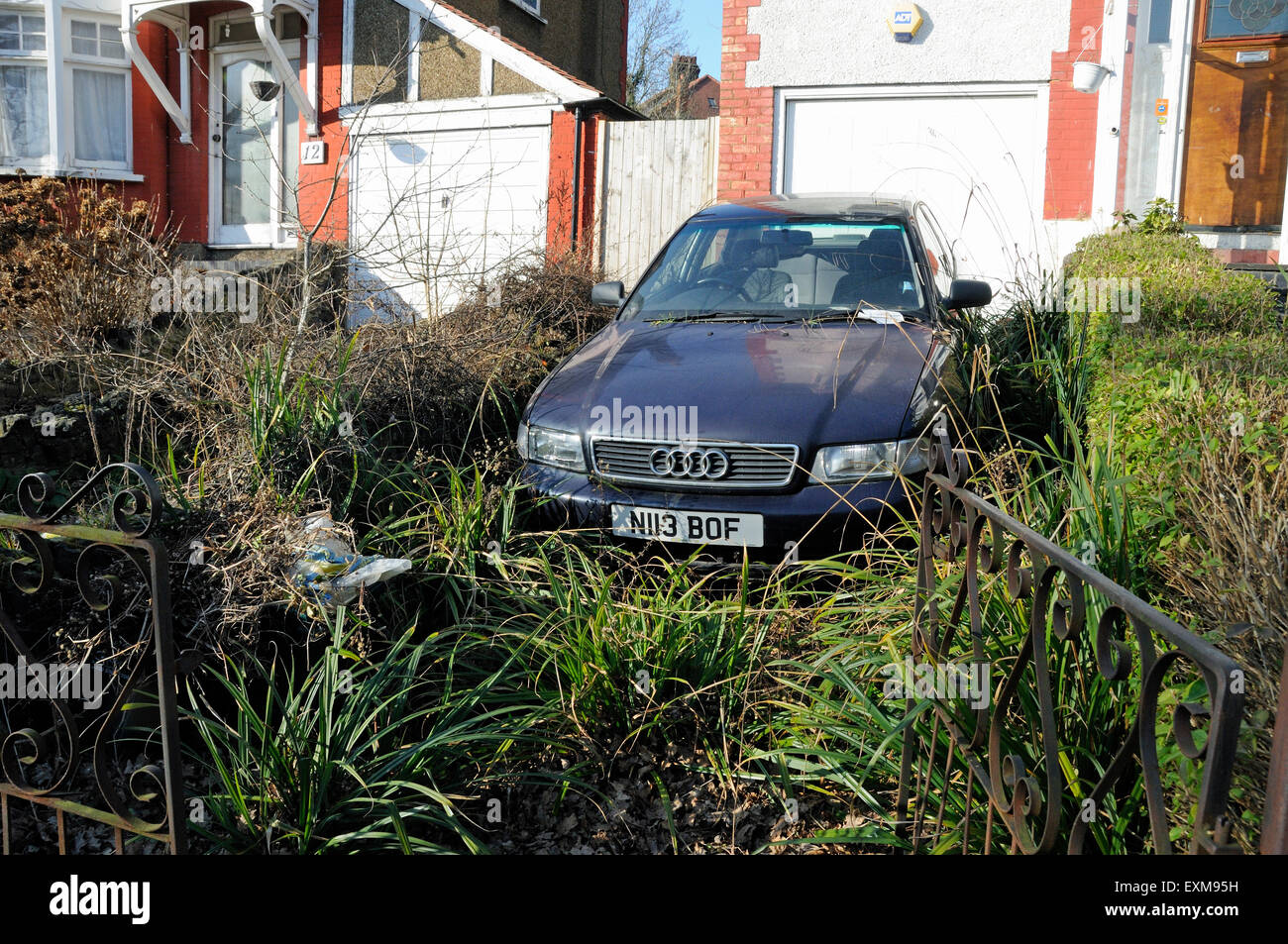 Car on overgrown suburban front drive from which it is unable to drive out, Bounds Green London Borough of Haringey England UK Stock Photo