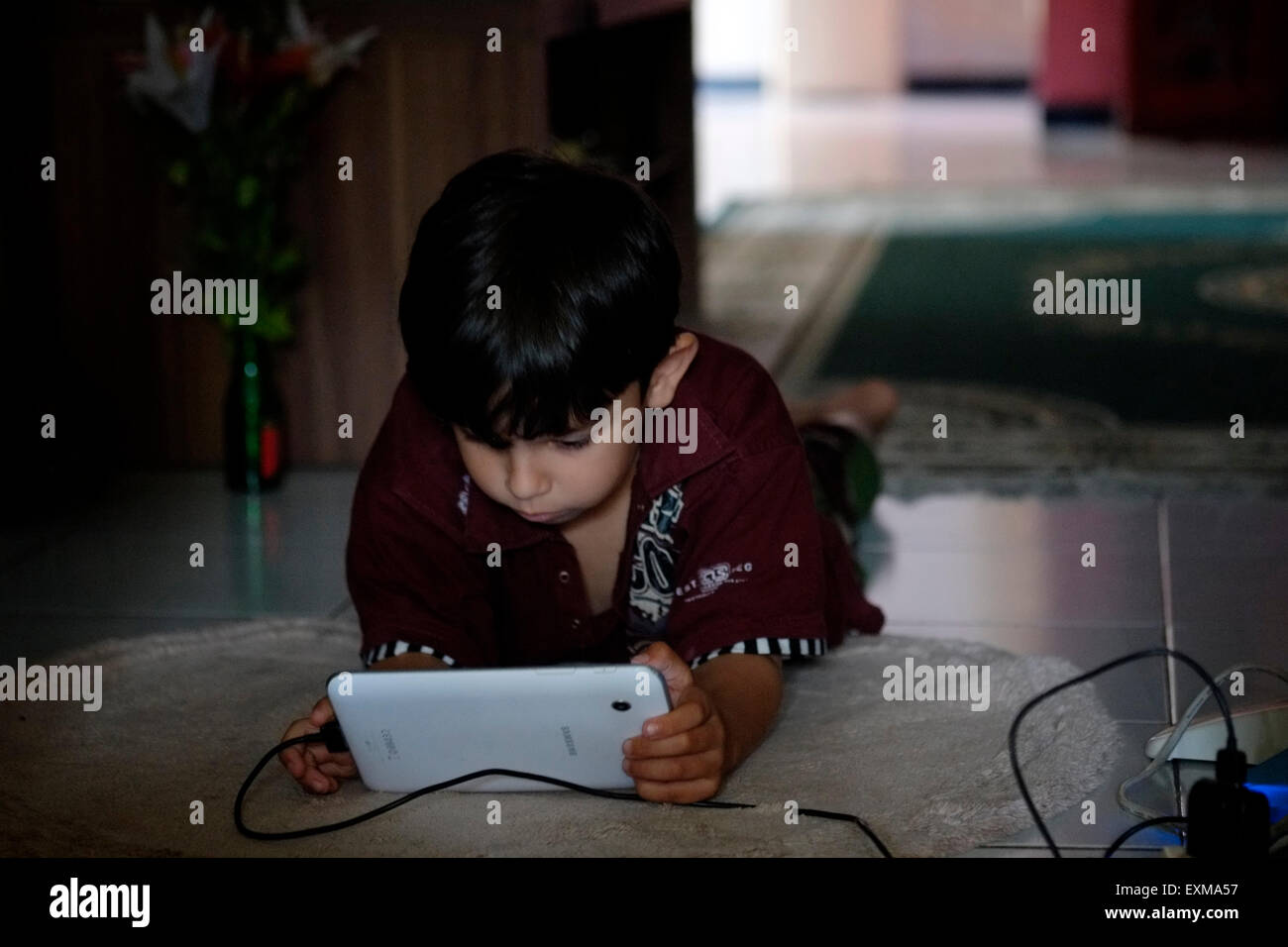 little boy playing games on a tablet at his home in java indonesia