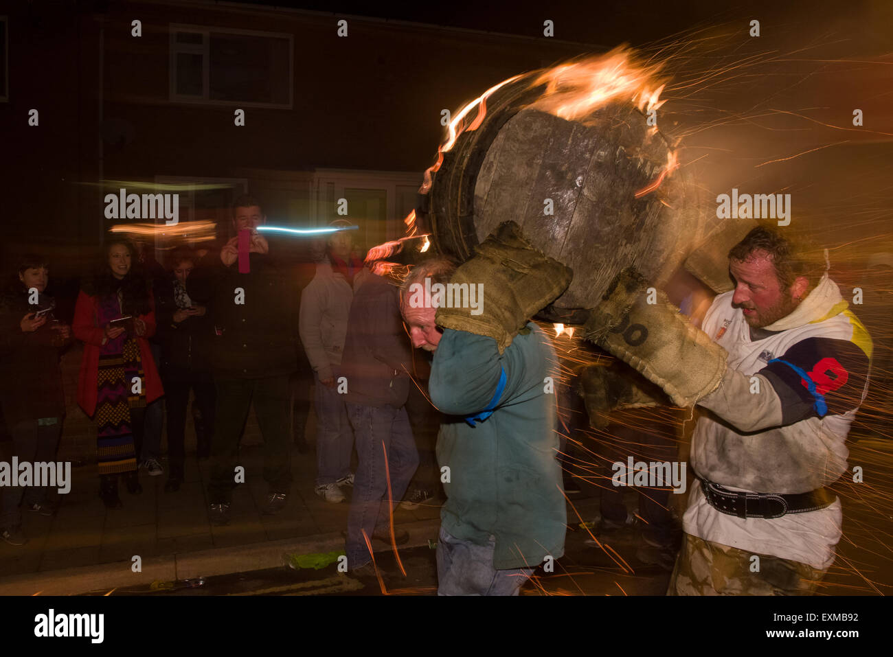Man carrying a burning barrel on Yonder Street, to mark Bonfire Night, 5 November, at the Tar Barrels festival, Ottery St Mary, Devon, England Stock Photo
