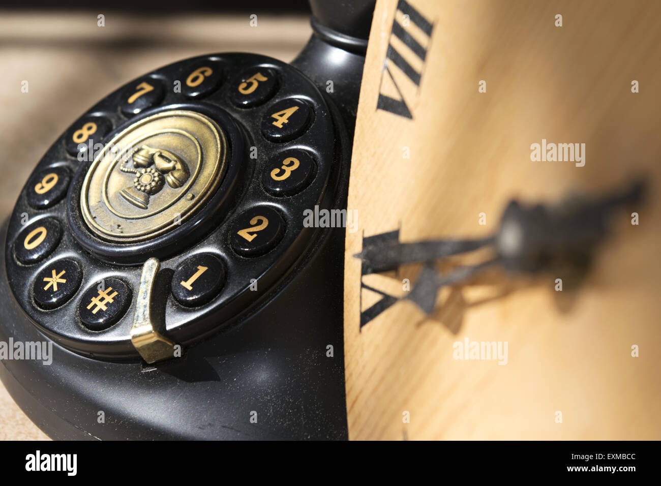 clock with roman enumeration  and black antique phone with manual keys Stock Photo