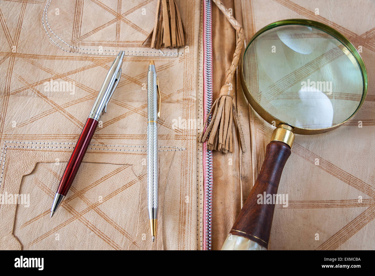 Magnifying Glass And Two Pens On Leather Folder Stock Photo - Alamy