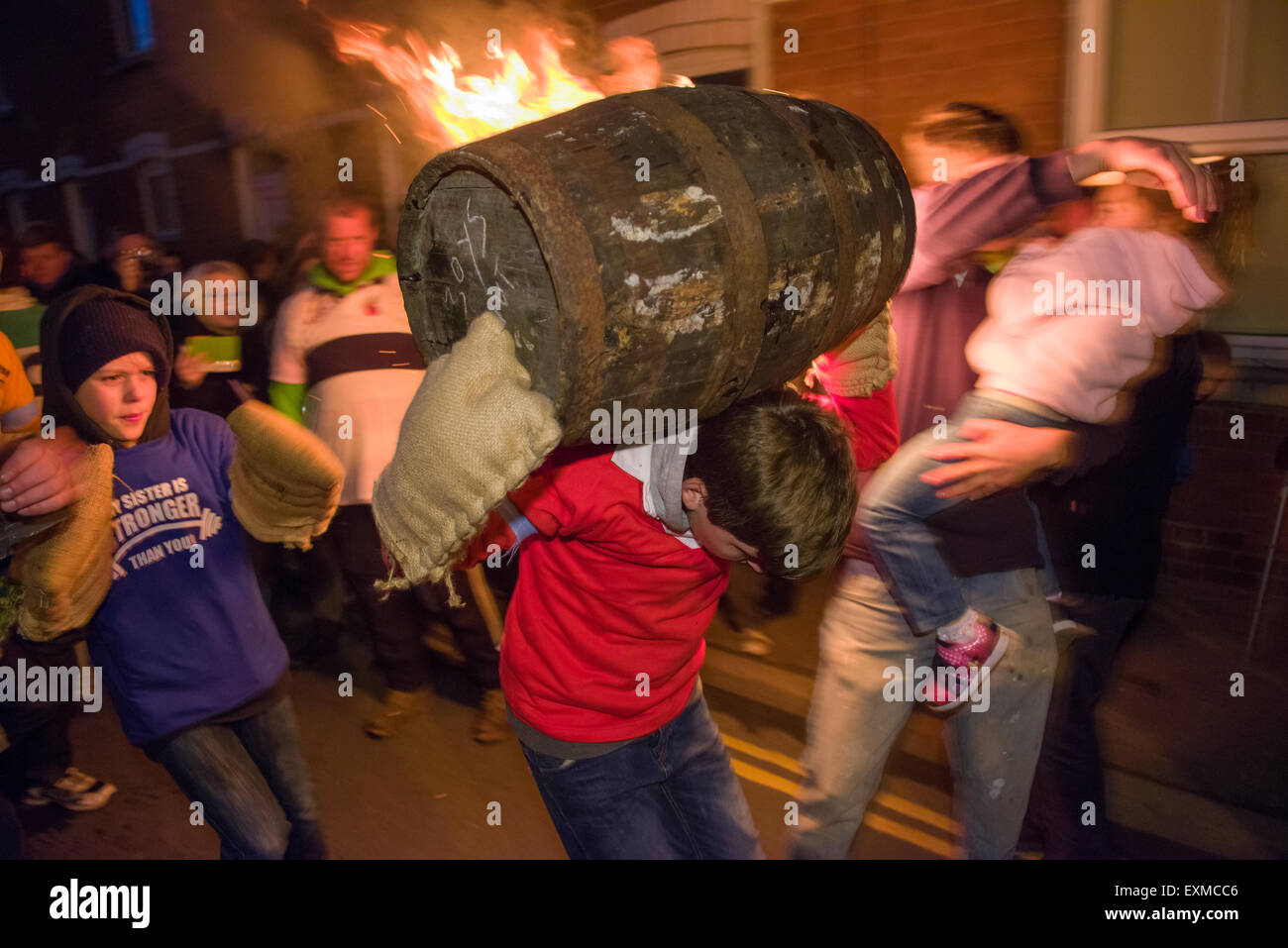 Child carrying a burning barrel to mark Bonfire Night, 5 November, at the Tar Barrels festival, Ottery St Mary, Devon, England Stock Photo