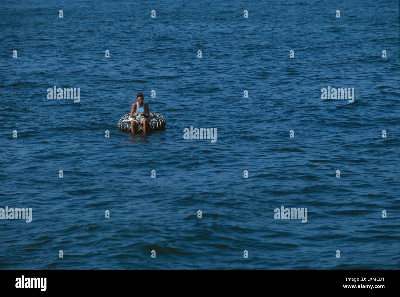 Man fishing in the Canal de Negara in an inflated car tyre, Havana, Cuba Stock Photo