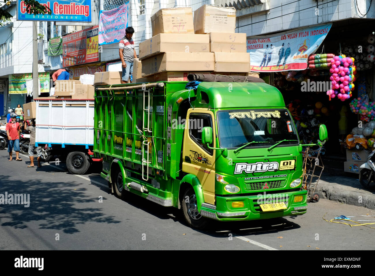 workers unload boxes from a dangerously overladen lorry as they deliver goods to a shop in solo java indonesia Stock Photo