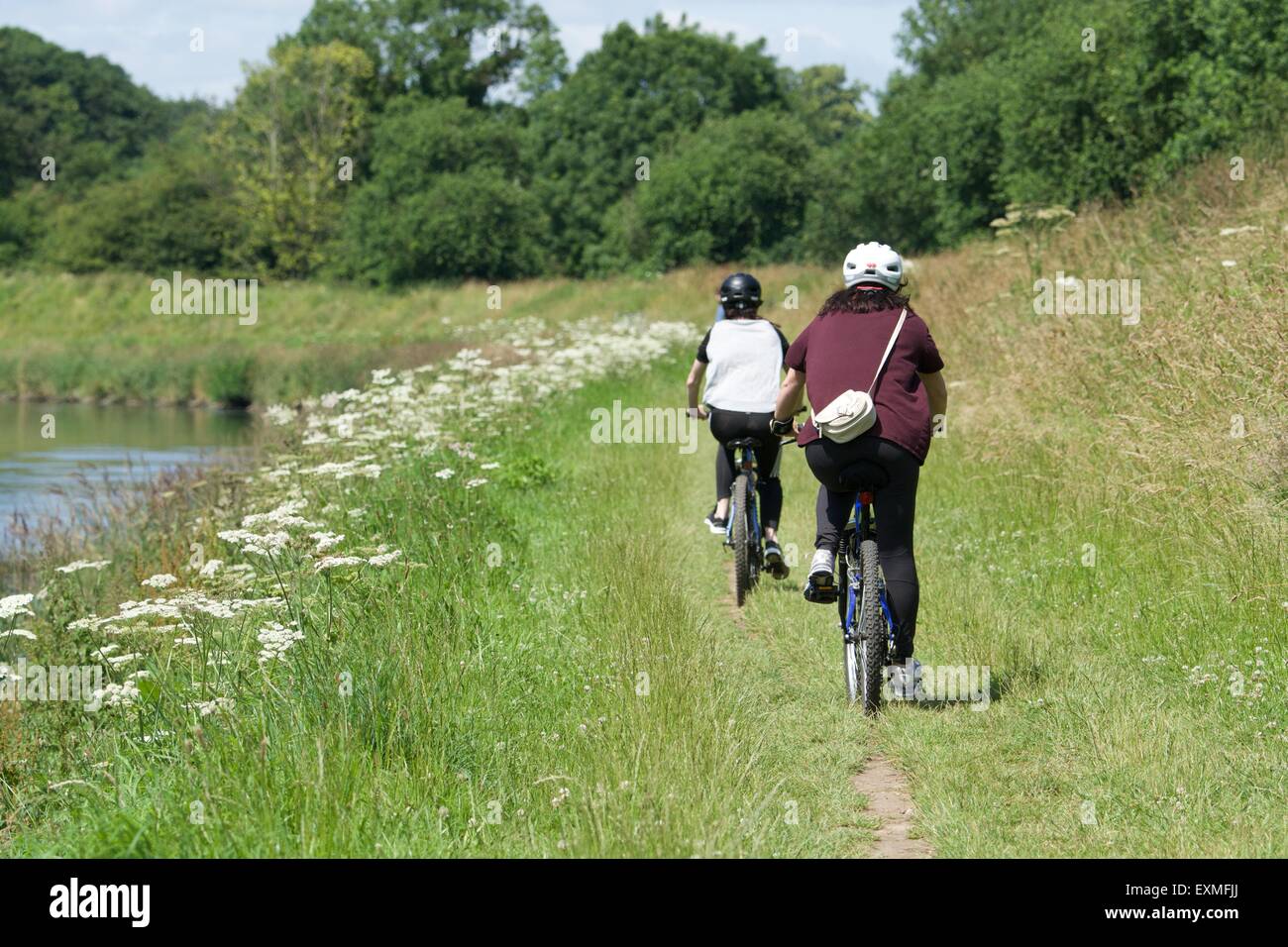 Two cyclists ride along a path along the bank of the the River Mersey as it passes between Didsbury and Northenden in south Manchester. Stock Photo