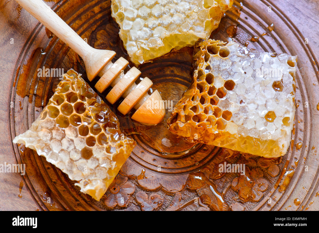 Honeycomb with honey dipper on vintage wooden plate background Stock Photo
