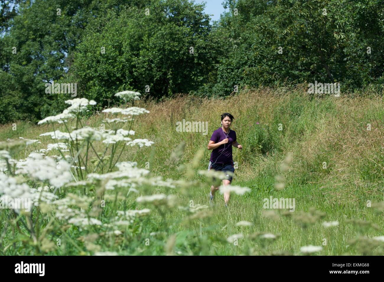 A jogger runs along a path along the banks of the the River Mersey as it passes between Didsbury and Northenden in south Manchester. Stock Photo