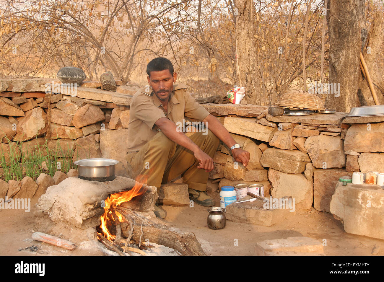 Forest guard cooking on open firewood kitchen ; Ranthambore National Park ; Sawai Madhopur ; Rajasthan ; India ; Asia Stock Photo
