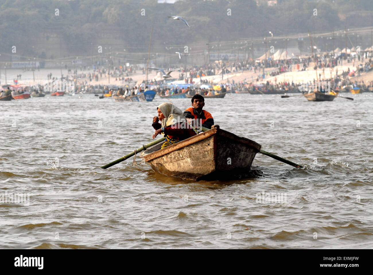 Devotee sit in boat arriving at confluence of Ganges; Yamuna and Saraswati rivers to take holy dip Ardh Kumbh Mela Allahabad Stock Photo